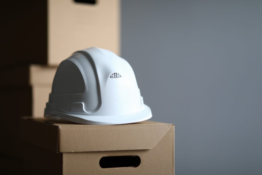 Cardboard box lies white protective helmet builder